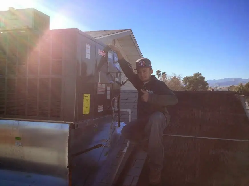 HVAC technician performing Air Duct Cleaning on a rooftop unit in Lockhart